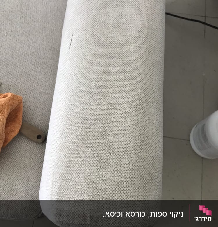 ספה בהירה עם מגבת כתומה וחומר ניקוי